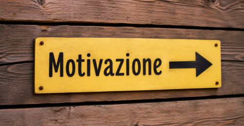 Cartello giallo con scritta Motivazione e freccia verso destra fissato su parete di assi in legno chiaro stile wengè